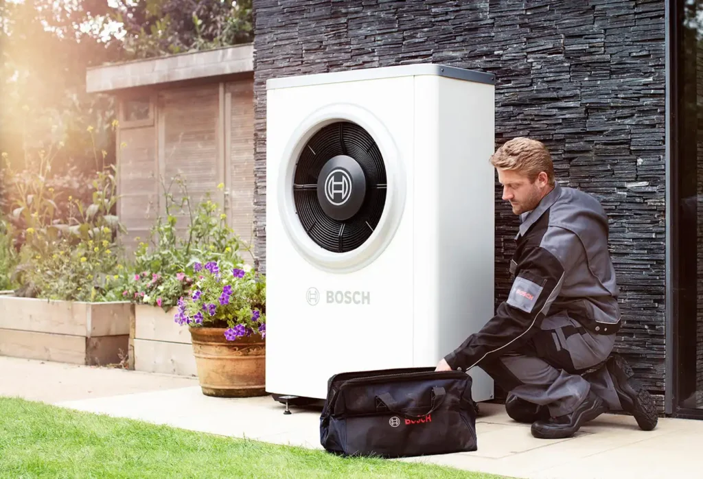 Bosch heat pump unit installed outside with a technician adjusting it.